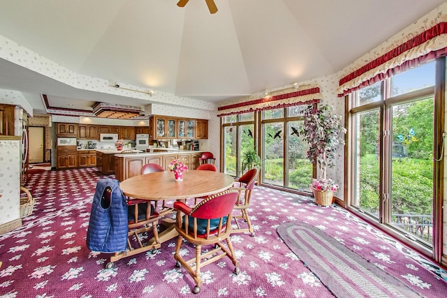 dining area with ceiling fan, carpet floors, and high vaulted ceiling