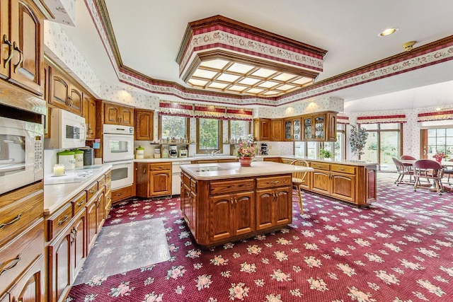 kitchen featuring crown molding, white appliances, a healthy amount of sunlight, and a kitchen island