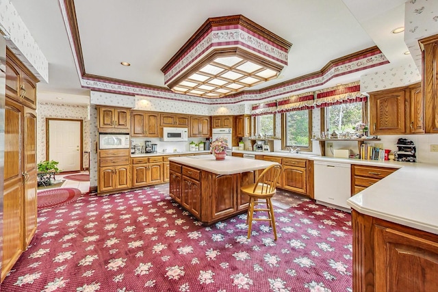 kitchen featuring a kitchen island, sink, a kitchen bar, ornamental molding, and white appliances