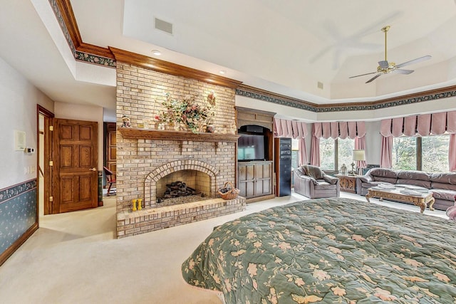 living room with crown molding, ceiling fan, a tray ceiling, a fireplace, and light carpet