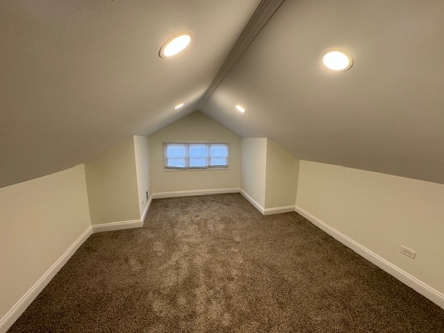 bonus room featuring vaulted ceiling with beams and dark carpet