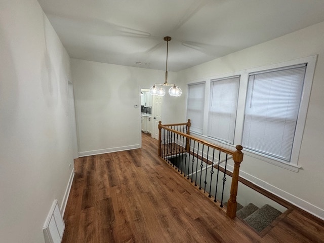 staircase with hardwood / wood-style floors and a notable chandelier