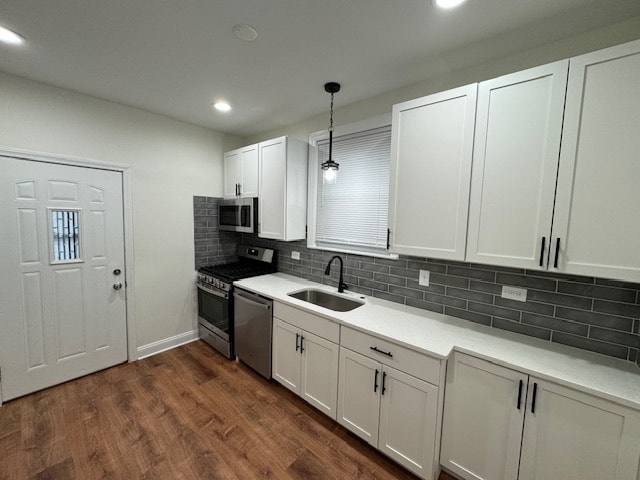 kitchen with stainless steel appliances, white cabinets, dark wood-type flooring, sink, and hanging light fixtures