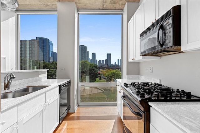 kitchen with black appliances, white cabinetry, and a wealth of natural light