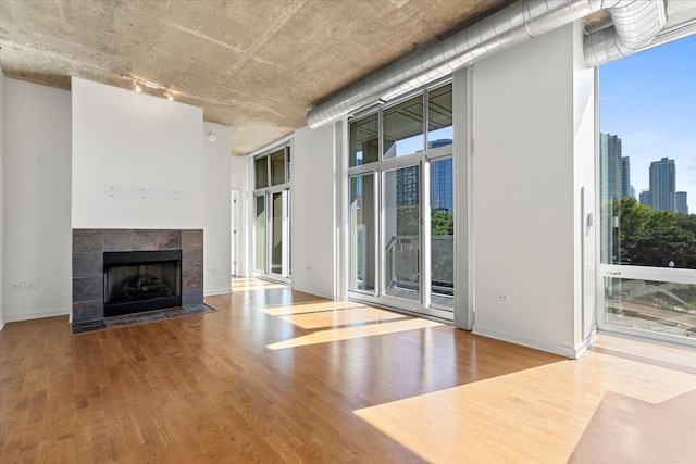 unfurnished living room with wood-type flooring and a tile fireplace