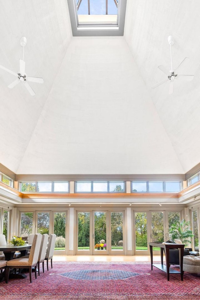 living room featuring ceiling fan, a healthy amount of sunlight, and a high ceiling