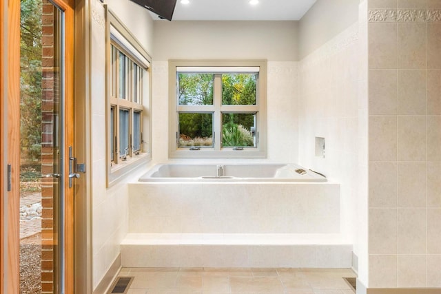 bathroom with tile patterned floors and tiled tub