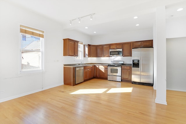 kitchen featuring stainless steel appliances, sink, light hardwood / wood-style flooring, and track lighting