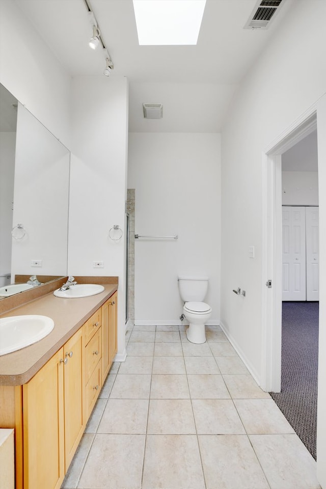 bathroom with vanity, a skylight, an enclosed shower, rail lighting, and toilet