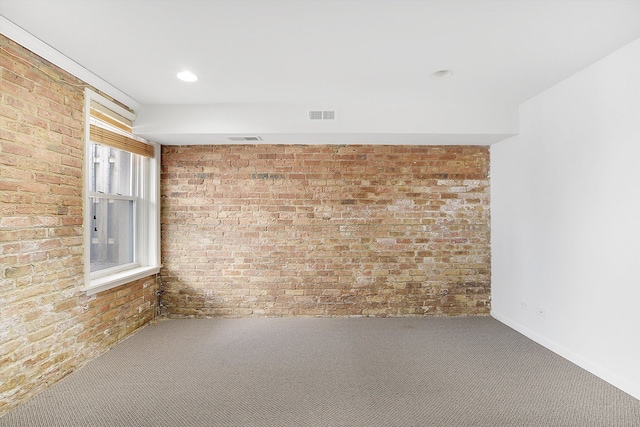 unfurnished room featuring carpet and brick wall