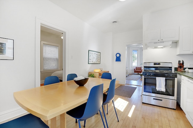 kitchen with ceiling fan, light wood-type flooring, stainless steel gas range oven, and white cabinetry