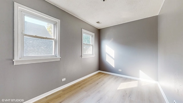 unfurnished room featuring light hardwood / wood-style floors and a textured ceiling