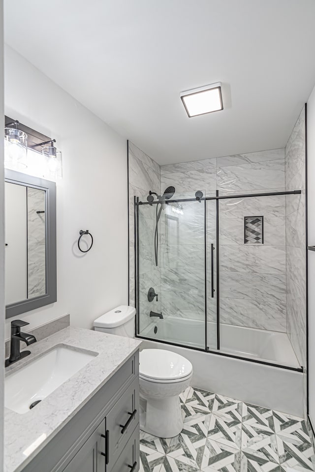 full bathroom featuring vanity, combined bath / shower with glass door, toilet, and tile patterned floors