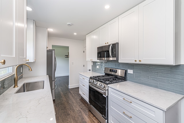 kitchen with dark hardwood / wood-style floors, backsplash, stainless steel gas range, light stone countertops, and white cabinetry