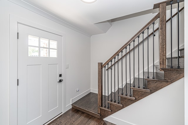 foyer entrance with ornamental molding and dark wood-type flooring