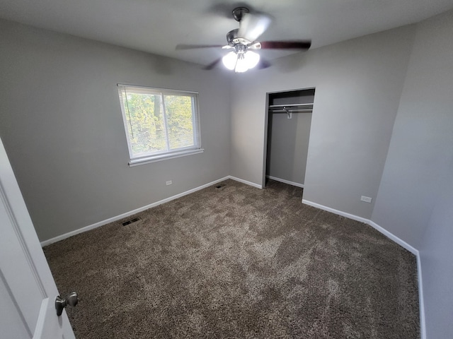 unfurnished bedroom with a closet, dark carpet, and ceiling fan