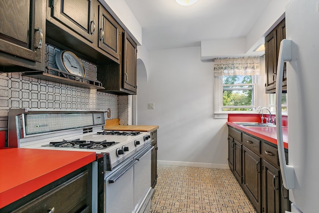 kitchen with decorative backsplash, white appliances, sink, and dark brown cabinets