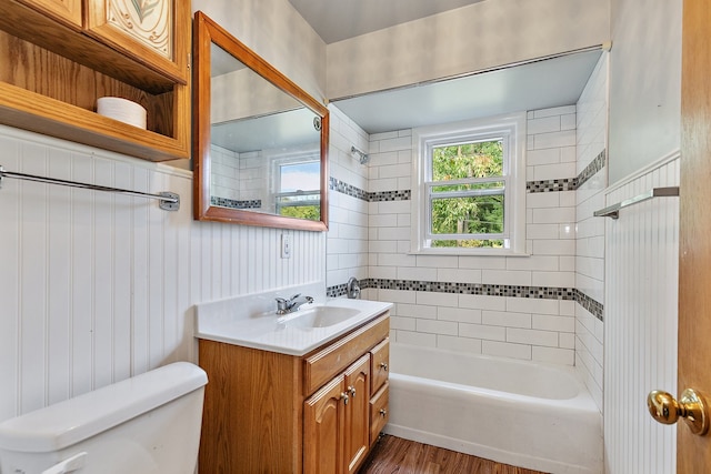 full bathroom featuring vanity, wood-type flooring, tiled shower / bath combo, wood walls, and toilet