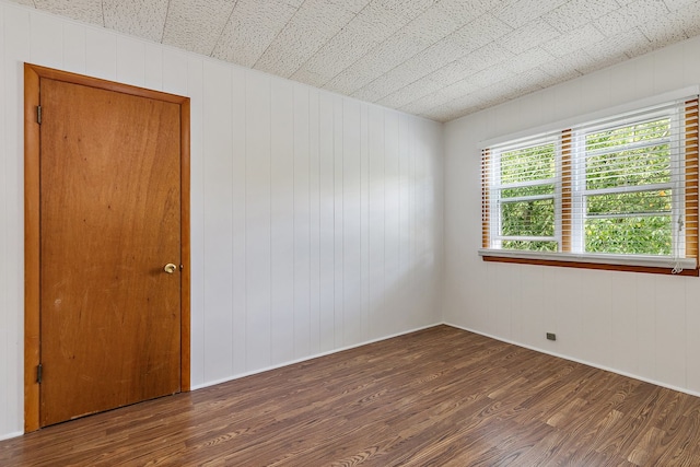 spare room with dark hardwood / wood-style floors and wooden walls