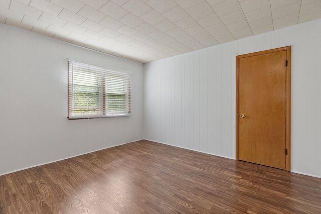 spare room with wood walls and dark wood-type flooring