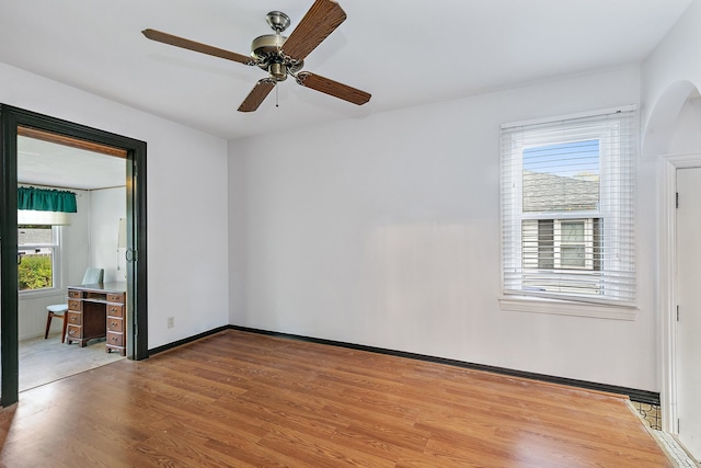 spare room featuring wood-type flooring, plenty of natural light, and ceiling fan