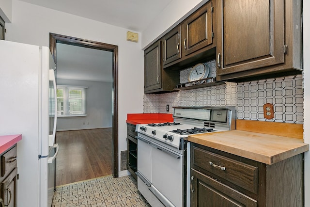 kitchen featuring white appliances, dark brown cabinetry, light hardwood / wood-style flooring, wood counters, and backsplash