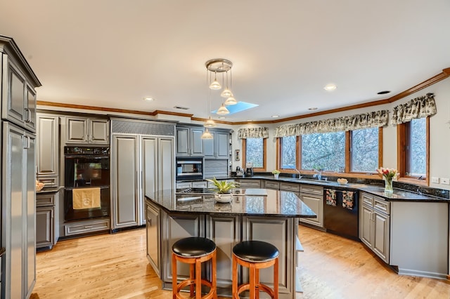 kitchen with a skylight, a kitchen island, crown molding, and black appliances