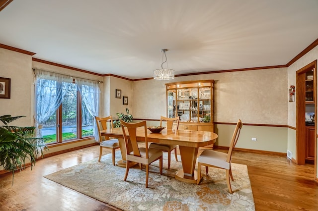 dining space featuring a notable chandelier, light wood-type flooring, and ornamental molding