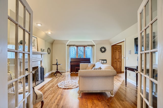 living room with french doors, light hardwood / wood-style flooring, and vaulted ceiling