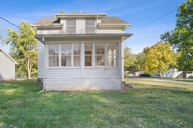 view of side of home with a sunroom and a lawn