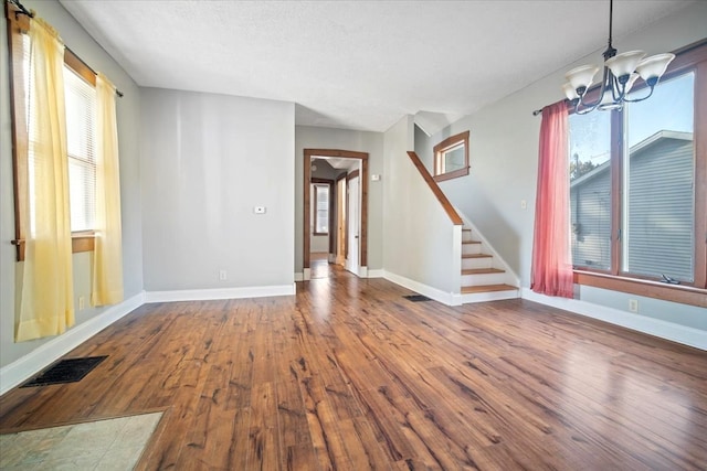 spare room with hardwood / wood-style floors, an inviting chandelier, and a textured ceiling