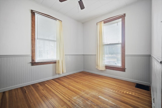 empty room featuring ceiling fan, hardwood / wood-style floors, and a wealth of natural light