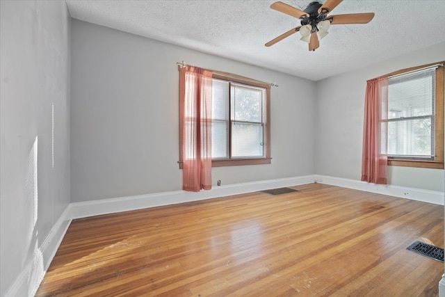 spare room featuring wood-type flooring, ceiling fan, and a textured ceiling