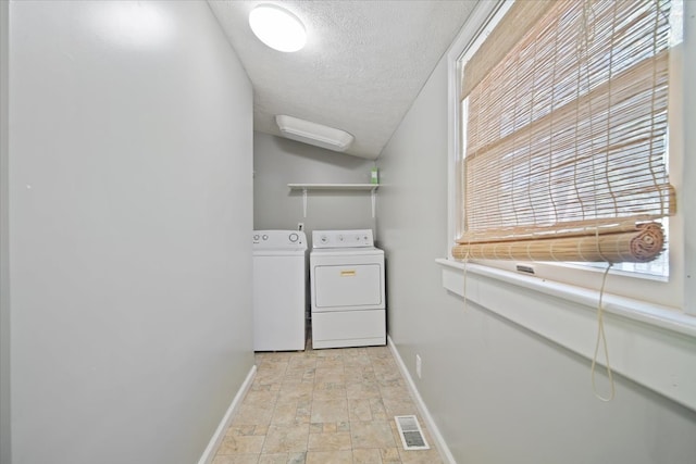 laundry room with washer and dryer, a healthy amount of sunlight, and a textured ceiling