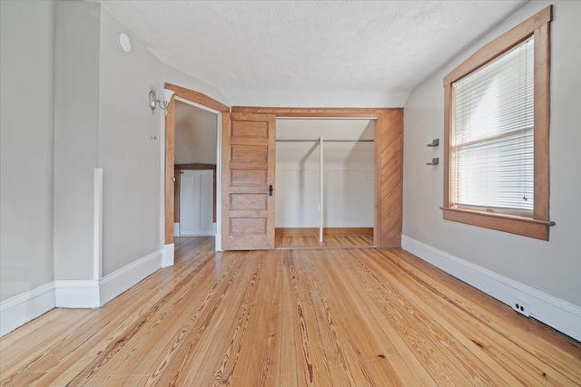 unfurnished bedroom featuring a closet, light hardwood / wood-style floors, and a textured ceiling