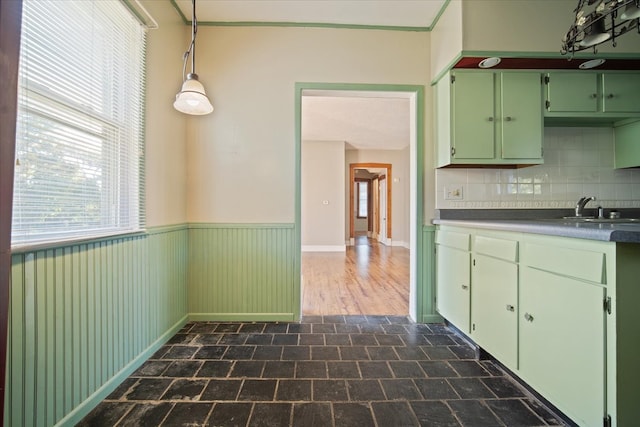 kitchen with green cabinetry, hanging light fixtures, backsplash, and sink