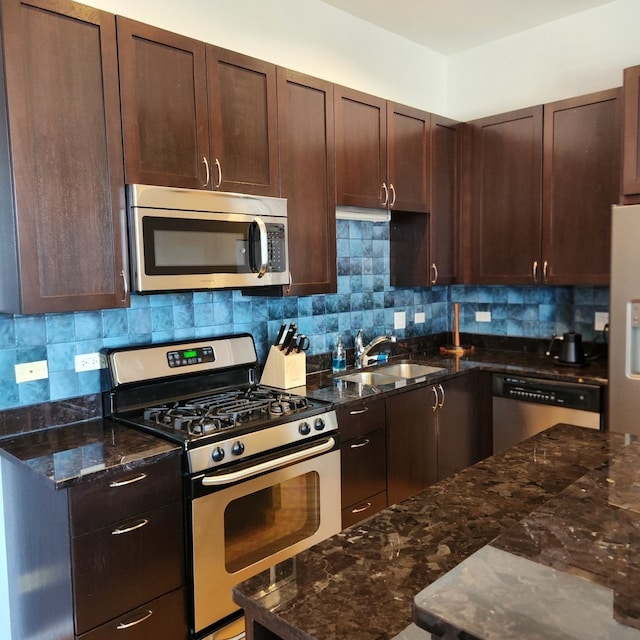 kitchen with dark stone counters, sink, stainless steel appliances, and tasteful backsplash