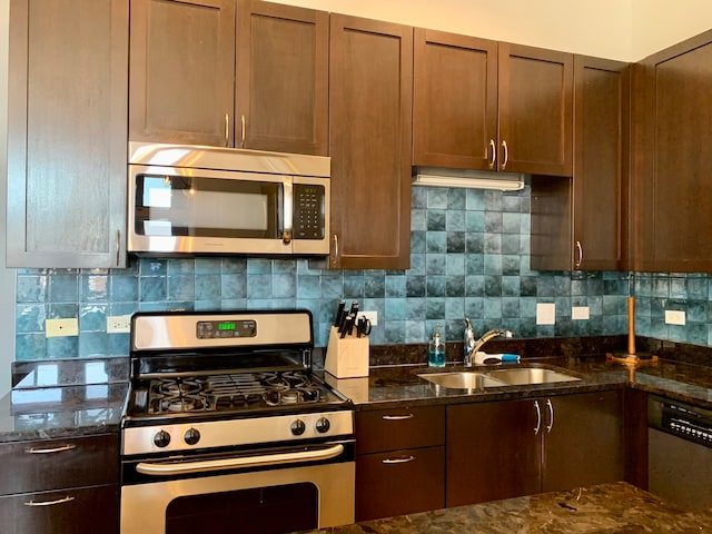 kitchen featuring appliances with stainless steel finishes, sink, dark stone counters, and decorative backsplash