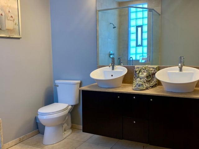 bathroom featuring a shower with door, tile patterned floors, vanity, and toilet