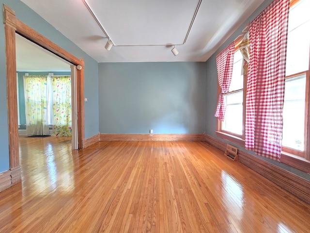 spare room featuring rail lighting and light hardwood / wood-style flooring