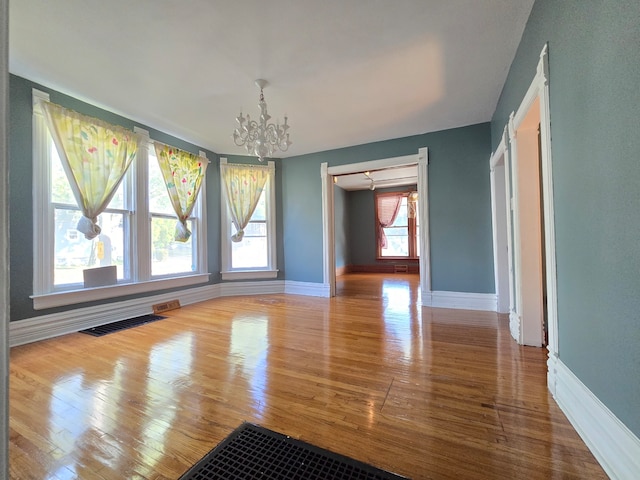 unfurnished dining area featuring a healthy amount of sunlight, a chandelier, and wood-type flooring