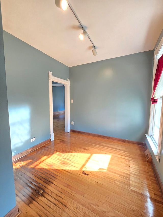 unfurnished room featuring hardwood / wood-style floors and rail lighting