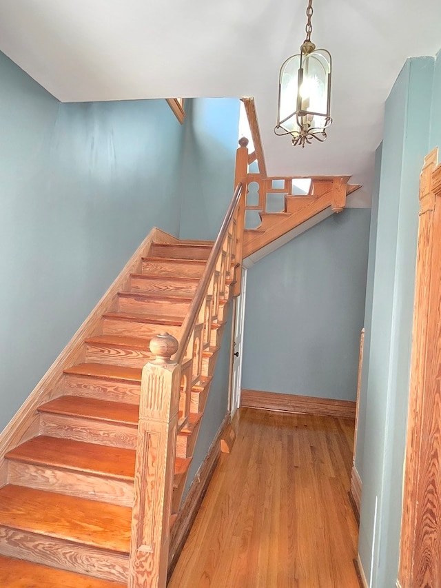 stairs with an inviting chandelier and hardwood / wood-style flooring