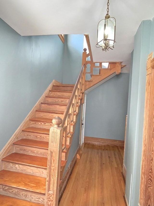 702 Franklin St, Waukegan, IL 60085 - stairway featuring a chandelier, wood finished floors, and baseboards