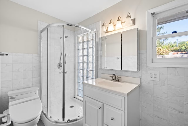 bathroom with an enclosed shower, vanity, tile walls, and toilet