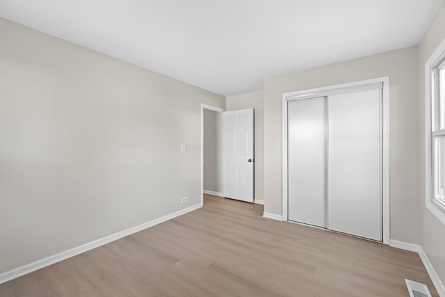 unfurnished bedroom featuring a closet, light hardwood / wood-style flooring, and multiple windows