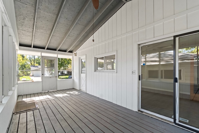 unfurnished sunroom featuring ceiling fan, vaulted ceiling, and a wealth of natural light