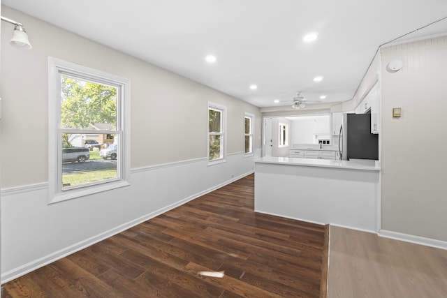 kitchen featuring ceiling fan, dark hardwood / wood-style floors, white cabinets, stainless steel fridge, and kitchen peninsula