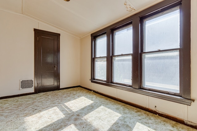 carpeted empty room featuring lofted ceiling