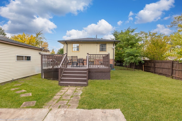 back of property with a wooden deck and a lawn